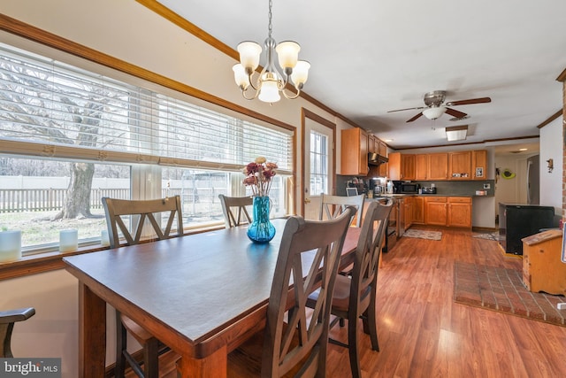 dining area featuring light wood-style flooring, ceiling fan with notable chandelier, and ornamental molding