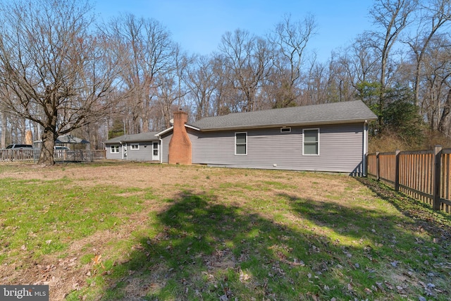 rear view of property featuring a fenced backyard and a lawn