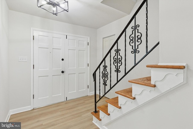 foyer with light wood-style flooring, baseboards, and stairs