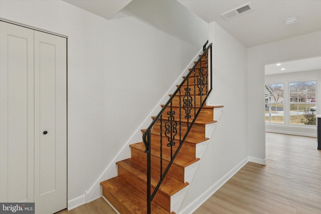 stairway with visible vents, baseboards, and wood finished floors