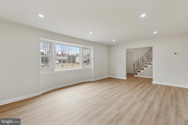 unfurnished living room featuring stairs, recessed lighting, baseboards, and light wood-style floors