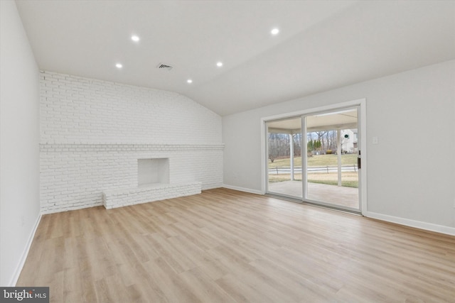 unfurnished living room featuring lofted ceiling, visible vents, light wood-style flooring, and brick wall