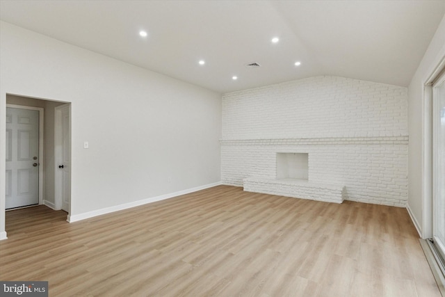 unfurnished living room featuring lofted ceiling, brick wall, visible vents, baseboards, and light wood-style floors