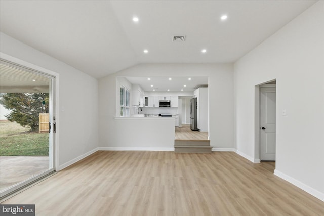 unfurnished living room with baseboards, light wood finished floors, a sink, and recessed lighting