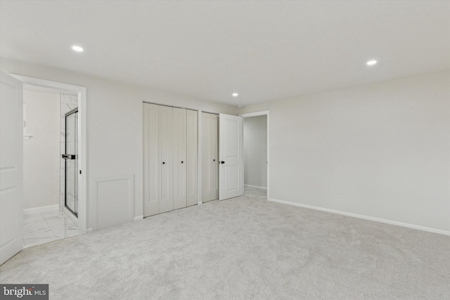 unfurnished bedroom with ensuite bath, baseboards, two closets, and recessed lighting