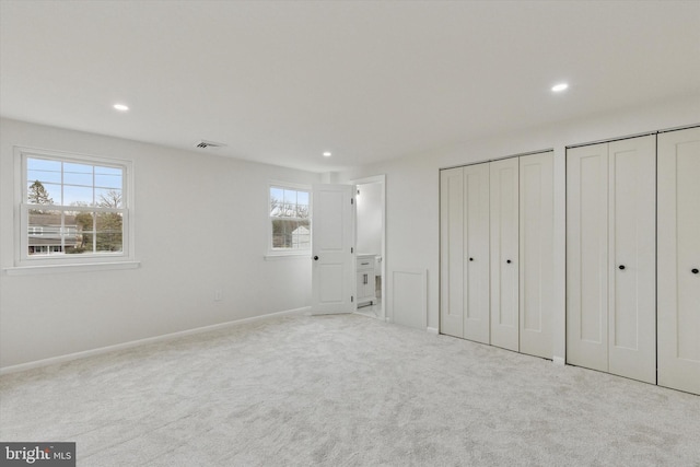 unfurnished bedroom featuring carpet floors, visible vents, two closets, and recessed lighting