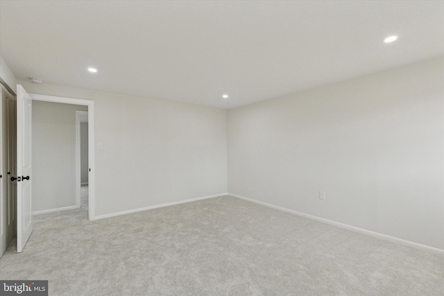 empty room featuring light carpet, baseboards, and recessed lighting