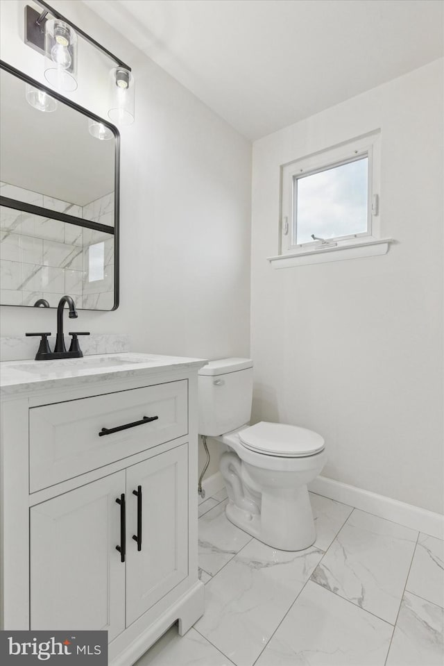 bathroom featuring marble finish floor, baseboards, vanity, and toilet