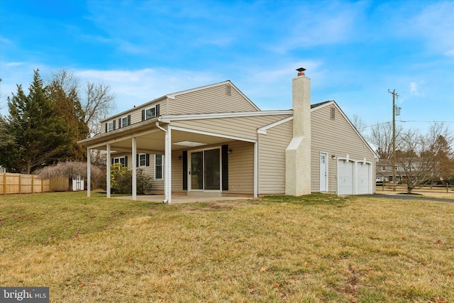 back of house with an attached garage, fence, a yard, a chimney, and a patio area