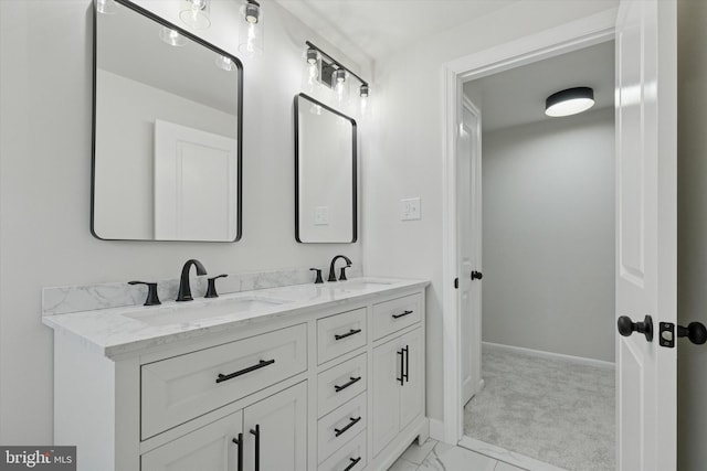 bathroom featuring marble finish floor, a sink, baseboards, and double vanity