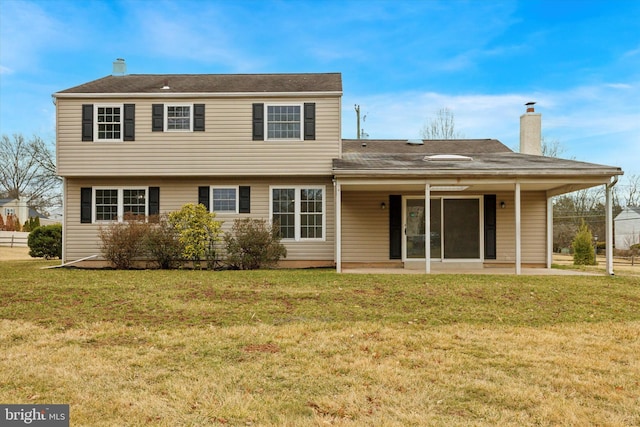 back of house with a chimney, a patio area, and a lawn