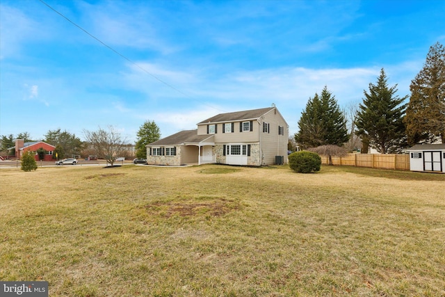 back of house featuring a yard, a storage unit, an outdoor structure, and fence