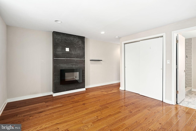 unfurnished living room featuring recessed lighting, baseboards, a fireplace, and light wood finished floors