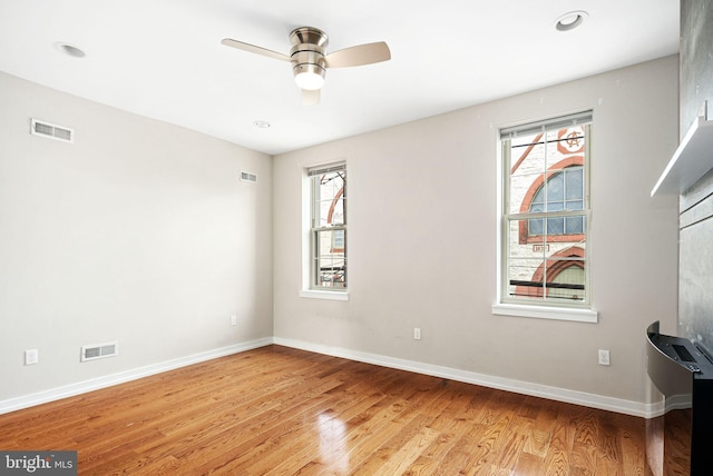 unfurnished room featuring a ceiling fan, visible vents, light wood-style flooring, and baseboards