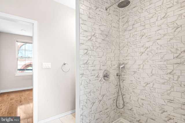 full bathroom with baseboards, tiled shower, and wood finished floors