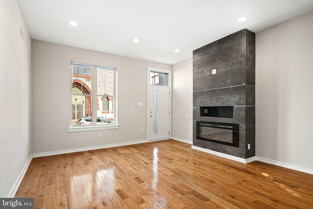 unfurnished living room with recessed lighting, a large fireplace, baseboards, and hardwood / wood-style flooring