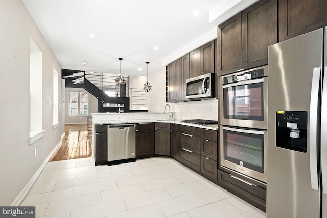 kitchen featuring dark brown cabinetry, stainless steel appliances, a sink, and light countertops