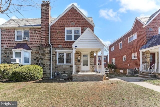 view of front of home with a front lawn, brick siding, central AC unit, and a chimney