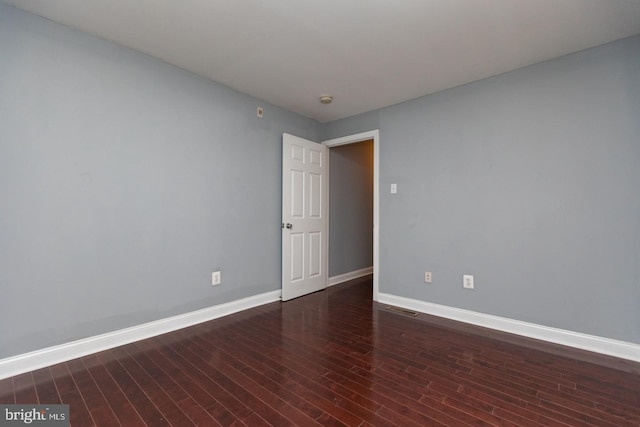 spare room featuring wood finished floors, visible vents, and baseboards