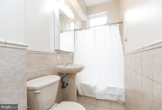 full bath featuring a wainscoted wall, tile patterned flooring, toilet, and tile walls