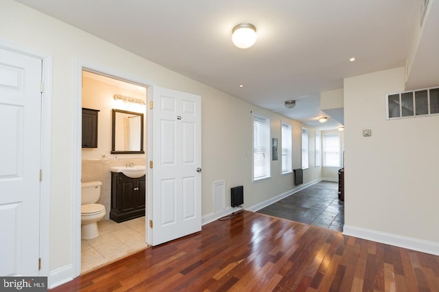 hallway with a sink, wood finished floors, and baseboards