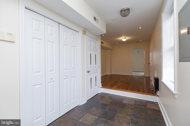 hall with baseboards, visible vents, and stone finish floor