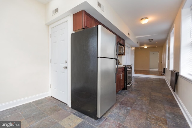 kitchen featuring appliances with stainless steel finishes, stone finish floor, visible vents, and baseboards