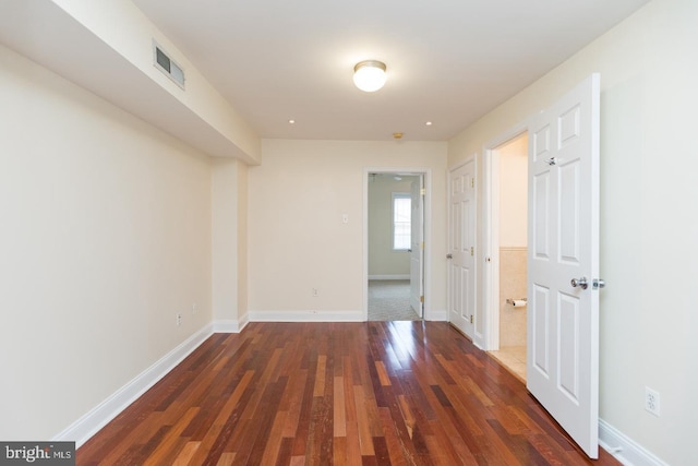 unfurnished room with dark wood-style floors, baseboards, and visible vents