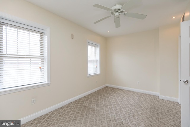 spare room featuring light carpet, ceiling fan, and baseboards