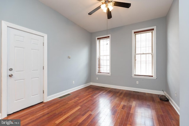 empty room featuring hardwood / wood-style flooring, visible vents, baseboards, and a ceiling fan