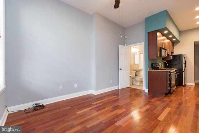 kitchen with dark wood-style floors, appliances with stainless steel finishes, a ceiling fan, and baseboards