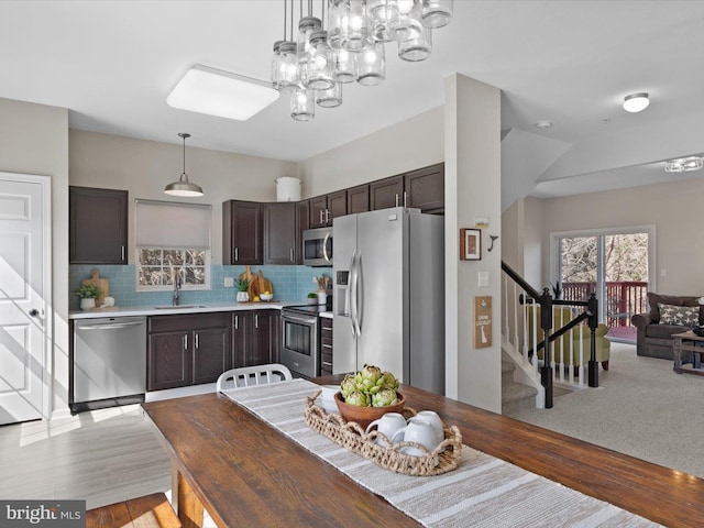 kitchen featuring tasteful backsplash, dark brown cabinets, light countertops, appliances with stainless steel finishes, and a sink