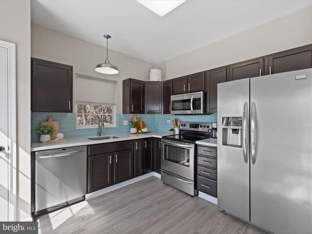 kitchen featuring a sink, tasteful backsplash, appliances with stainless steel finishes, light countertops, and dark brown cabinets