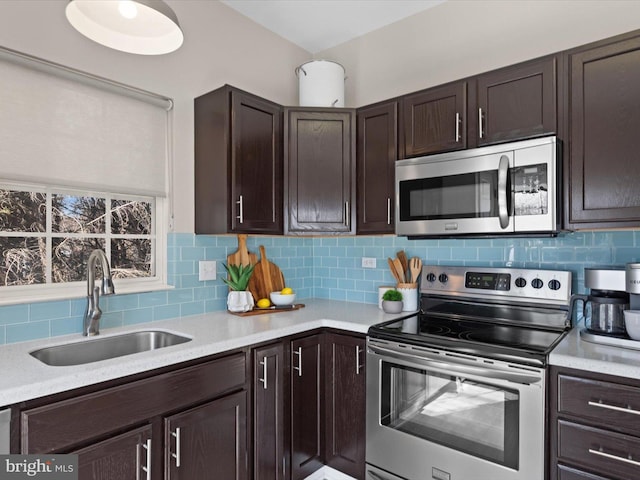 kitchen featuring a sink, backsplash, stainless steel appliances, light countertops, and dark brown cabinets