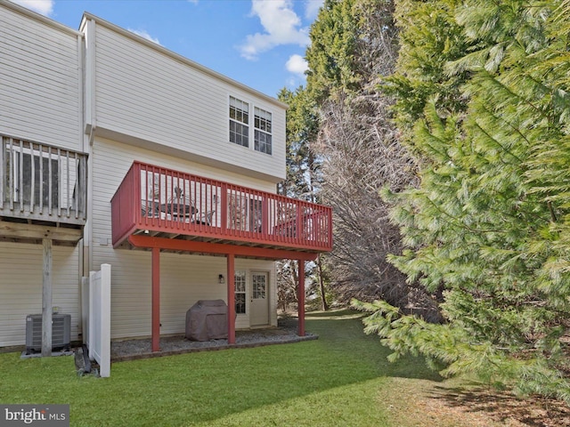 back of house featuring a wooden deck, a lawn, and central AC unit