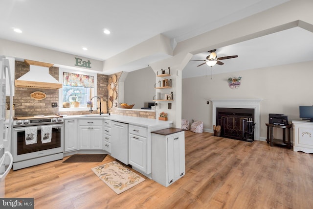 kitchen with custom range hood, a sink, range with electric stovetop, a glass covered fireplace, and dishwasher