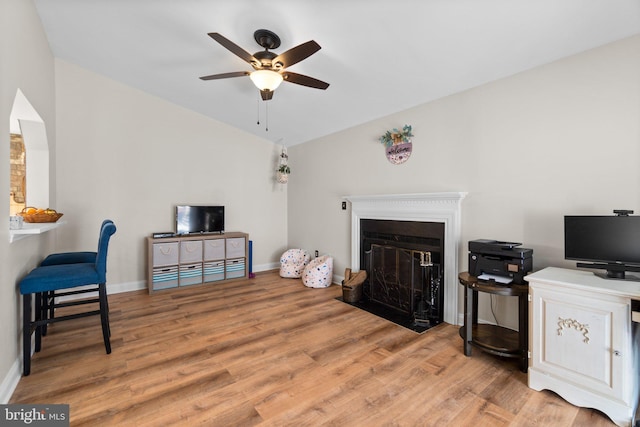 living room featuring baseboards, a fireplace with flush hearth, wood finished floors, and vaulted ceiling