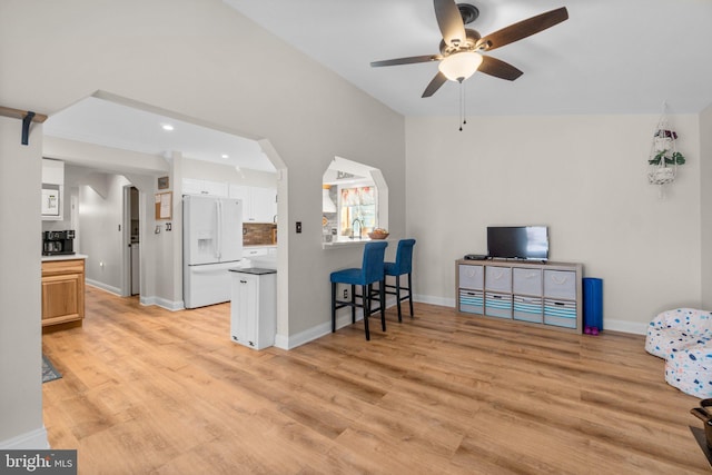 living room featuring light wood-type flooring, arched walkways, and baseboards