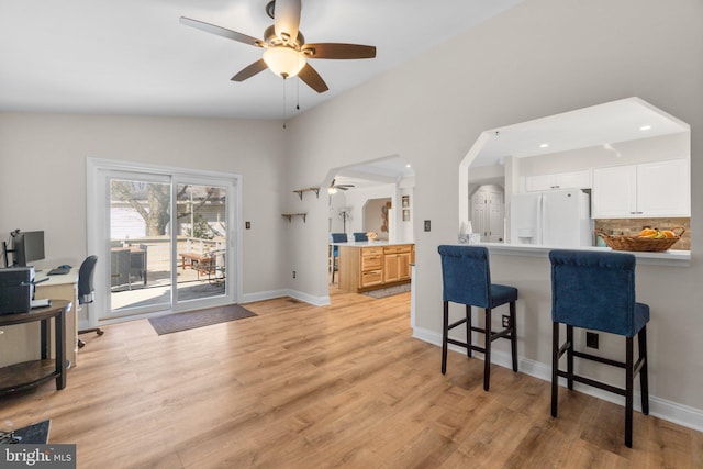 kitchen with a kitchen breakfast bar, backsplash, light wood-type flooring, and white fridge with ice dispenser