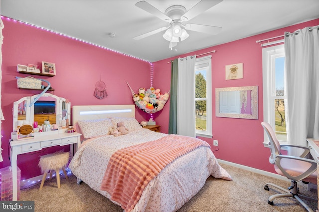 carpeted bedroom with multiple windows, a ceiling fan, and baseboards