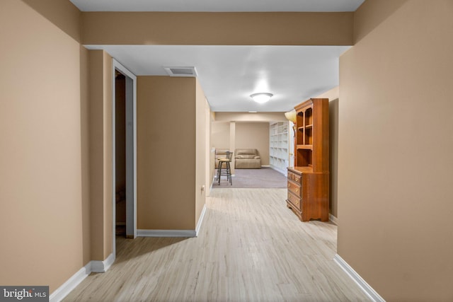 hallway with light wood-type flooring, baseboards, and visible vents