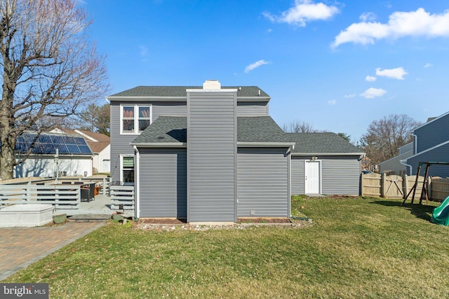 rear view of house featuring a patio, fence, a yard, roof with shingles, and a chimney