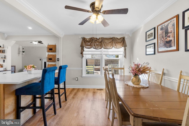 dining area featuring light wood finished floors, ceiling fan, crown molding, and baseboards