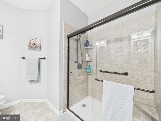 full bathroom with tile patterned flooring, a shower stall, toilet, and baseboards