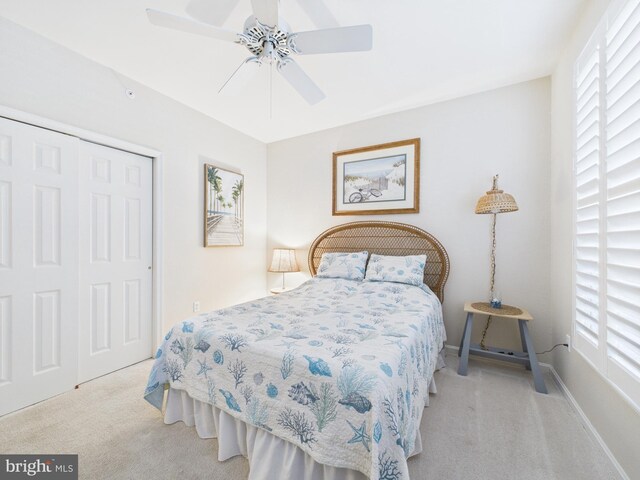 carpeted bedroom with ceiling fan, baseboards, and a closet