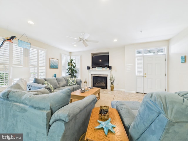 living area featuring tile patterned flooring, recessed lighting, a ceiling fan, baseboards, and a glass covered fireplace