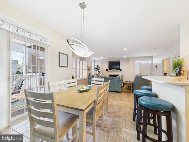 dining area featuring light tile patterned floors, plenty of natural light, and a fireplace