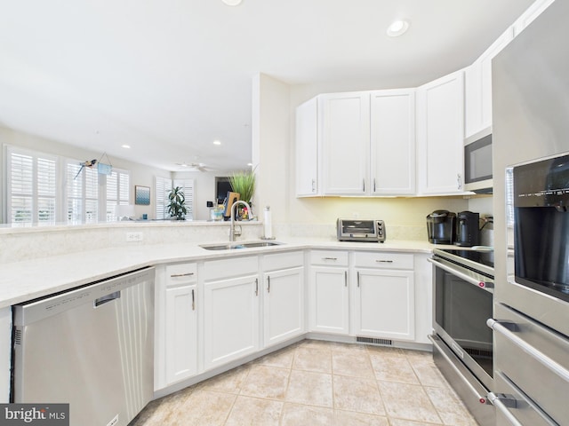 kitchen featuring appliances with stainless steel finishes, white cabinets, and a sink