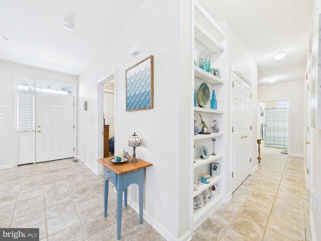 foyer entrance featuring light tile patterned floors and baseboards