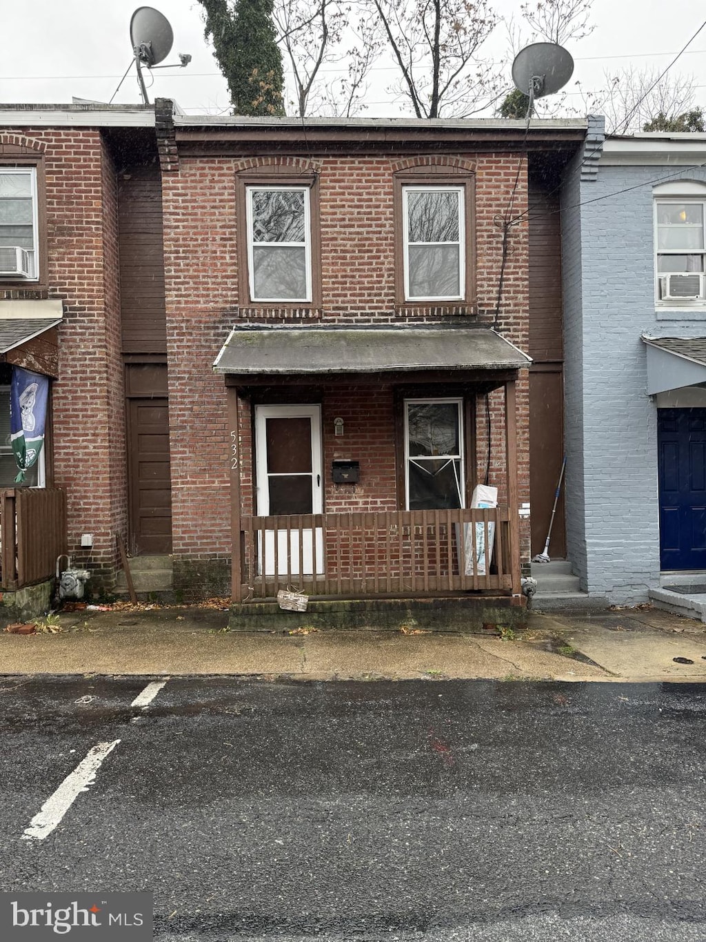 view of front facade featuring a porch, cooling unit, and brick siding